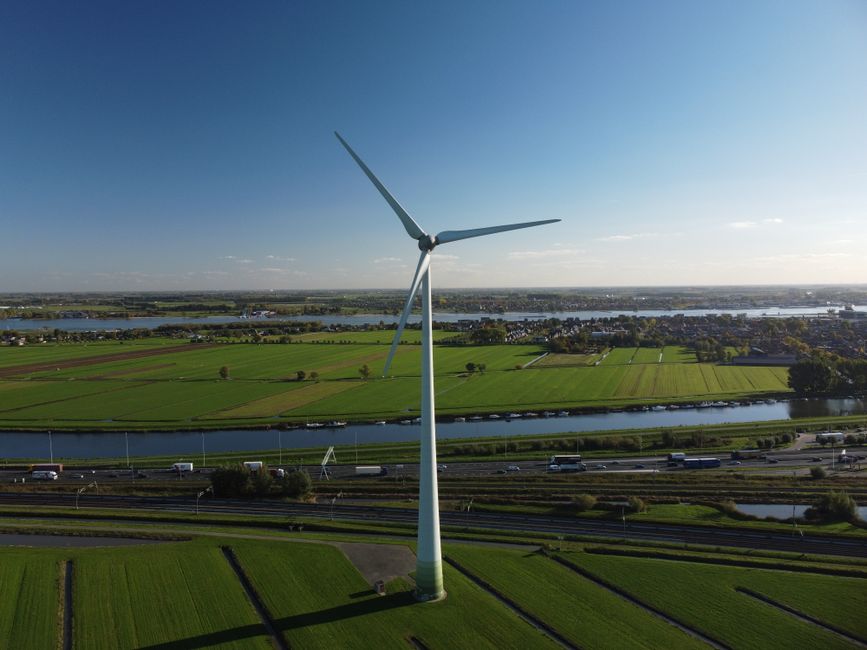 A scenic aerial view featuring a wind turbine in lush green farmland, showcasing renewable energy.